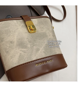 Detail of vintage canvas and leather bucket bag with gold-tone metal twist lock closure