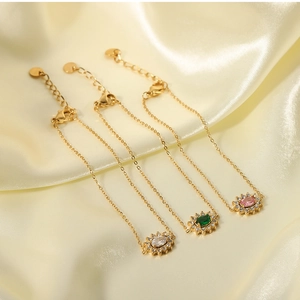 Detailed shot of three gold link bracelets with green, pink, and white crystal stones