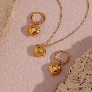Detail of gold polished heart pendant necklace and earrings set on mineral stones