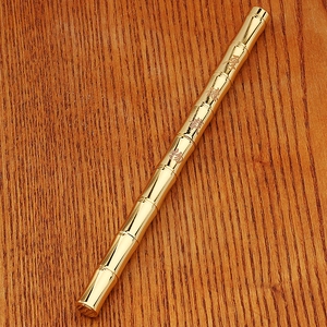 Macro detail of vintage bamboo-shaped brass pen with Chinese character engravings