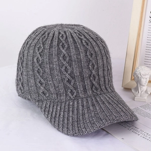 Detail view of dark grey knitted baseball cap featuring thick cable knit patterns