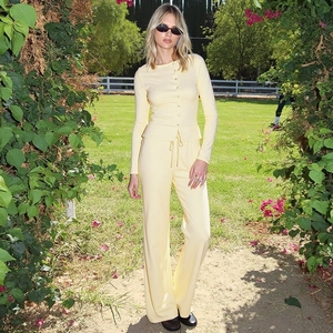 Detail of light yellow knit long sleeve cardigan and matching wide leg pants on a female model