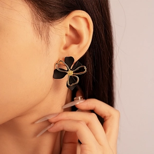 Detail shot of model wearing elegant double-layer black flower earrings with gold outlines