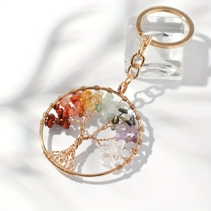 Gold tree of life keychain with colorful natural healing stones on white fabric background