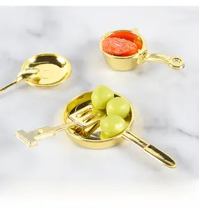 Macro shot of 5-piece gold miniature dollhouse cookware set on marble surface
