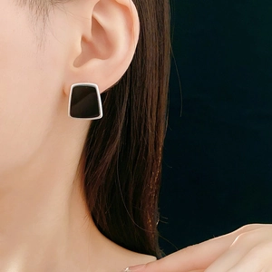 Gros plan d'un mannequin portant des boucles d'oreilles trapèze en résine noire et argent