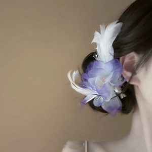 Elegant purple fabric flower hair clip with white feathers on a female model