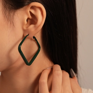 Close-up of minimalist dark green geometric diamond-shaped earring on a female model