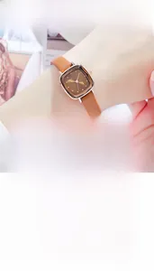 Detail of square rose gold watch with brown leather strap and minimalist brown dial