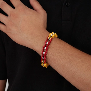 Detail eines rot-gelben Edelstahl-Fahrradkettenarmbands am Handgelenk eines Mannes