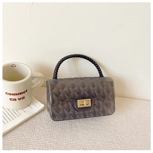 Detailed macro view of the smoked black jelly bag with gold twist lock and bead handle