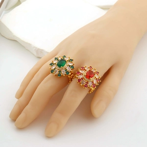 Detail view of gold adjustable rings featuring emerald and ruby stones on white marble