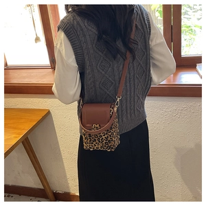 Rear view of a stylish leopard print crossbody bag with brown leather flap and golden hardware