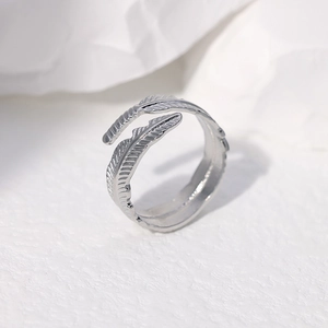Macro shot of silver feather ring showing adjustable open design and metallic texture