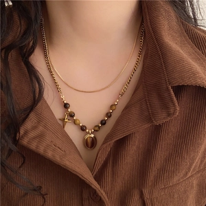 Detail of layered gold necklace with tiger eye stone pendants on a corduroy shirt