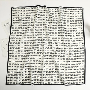 Detailed flat lay of a white silk scarf featuring black butterfly patterns and border