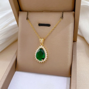 Detail of pear-cut emerald green gemstone pendant with diamond halo in a gift box