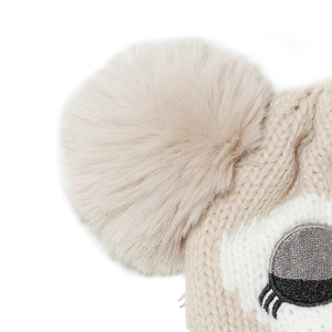 Macro view of beige cable knit texture and fluffy faux fur pom-pom on children's owl hat