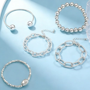 Detailed view of five silver-tone metal bracelets including beaded and link chain styles
