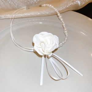 Détail d'une fleur de rose en tissu blanc et de perles d'imitation sur un collier chic