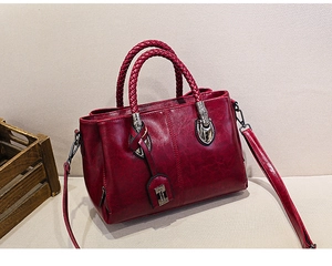 Detail of burgundy oil wax leather texture and woven handle on Boston handbag