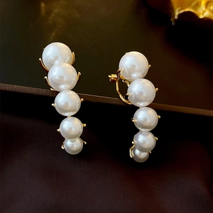 Detailed view of five white gradient pearls set in a sleek golden curved earrings base
