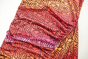 Close-up of the orange gradient floral print and side ruching detail on the dress