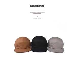 Dettaglio cappellini 5-panel in cotone nei colori beige, nero e grigio con occhielli