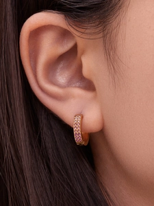Detailed close-up of a model wearing U-shaped gold earrings with pink zircon micro-pave