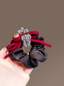 Detail of satin hair scrunchie with red velvet bow and black-white checkered bear