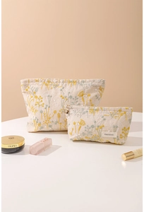 Vue détaillée de deux trousses à maquillage en coton et lin beige avec broderie florale