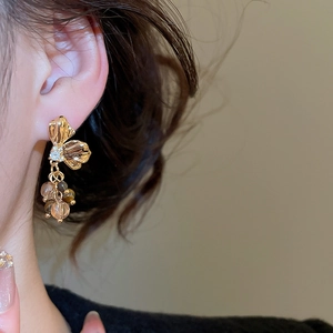 Detailed macro view of golden butterfly earrings with hanging brown zircon beads