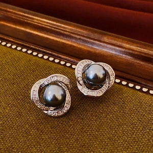 Macro view of vintage style black pearl stud earrings with sparkling crystal pavé spirals