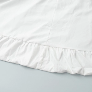 Détail de la robe en coton blanc avec ourlet à volants délicats et coutures premium