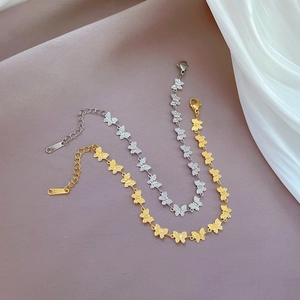 Detail of butterfly link bracelets in gold and silver finish with lobster clasp and tag