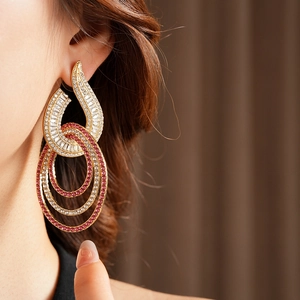 Detail of gold geometric hoop earrings with clear and pink zircon crystals on a model