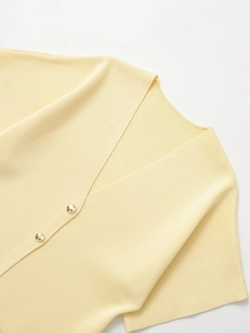 Detail of light yellow knit cardigan with V-neck and decorative gold metal buttons