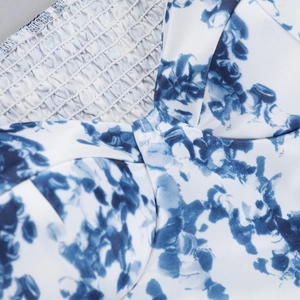 Gros plan du tissu imprimé floral bleu et des détails froncés de la robe d'été