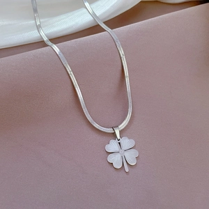 Macro shot of silver snake chain necklace featuring a minimalist clover flower pendant