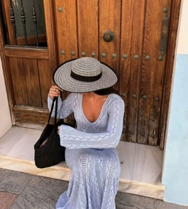 Détail de la robe en maille crochet bleu clair avec col en V, manches évasées et chapeau