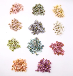 Flat lay of colorful 2cm mini silk daisy heads in eleven vibrant shades for DIY crafts