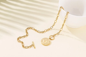 Detail of gold paperclip chain necklace with Saint Michael pendant and T-bar clasp