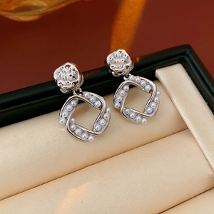 Detail view of silver earrings with textured metal and square pearl frame in jewelry box