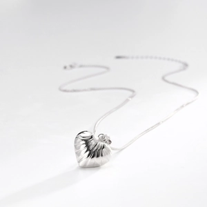 Macro shot of silver heart pendant featuring a unique textured finish on a delicate chain