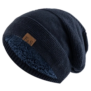 Detail of navy blue knitted beanie with thick fleece lining and brown leather F&S label
