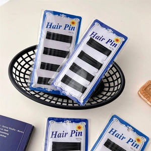 Close-up of black ball tip hair pins on card packaging in a stylish blue wire basket