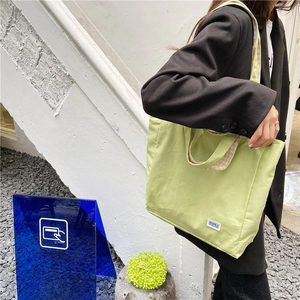 Bolso tote de lona verde claro con forro de cuadros y detalle de etiqueta de marca