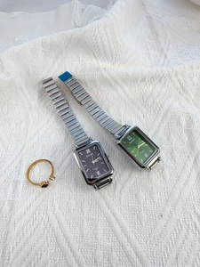 Detailed view of silver quartz watches with green and black rectangular sunray dials