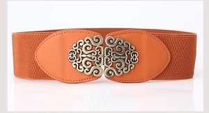Detail of orange elastic waist belt with vintage engraved metal buckle on white background