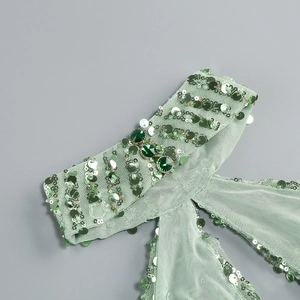 Detail of mint green mesh dress with silver sequins and three emerald-tone gemstones